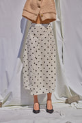 Mannequin wearing a beige cardigan, polka dot skirt, and black shoes on a white background