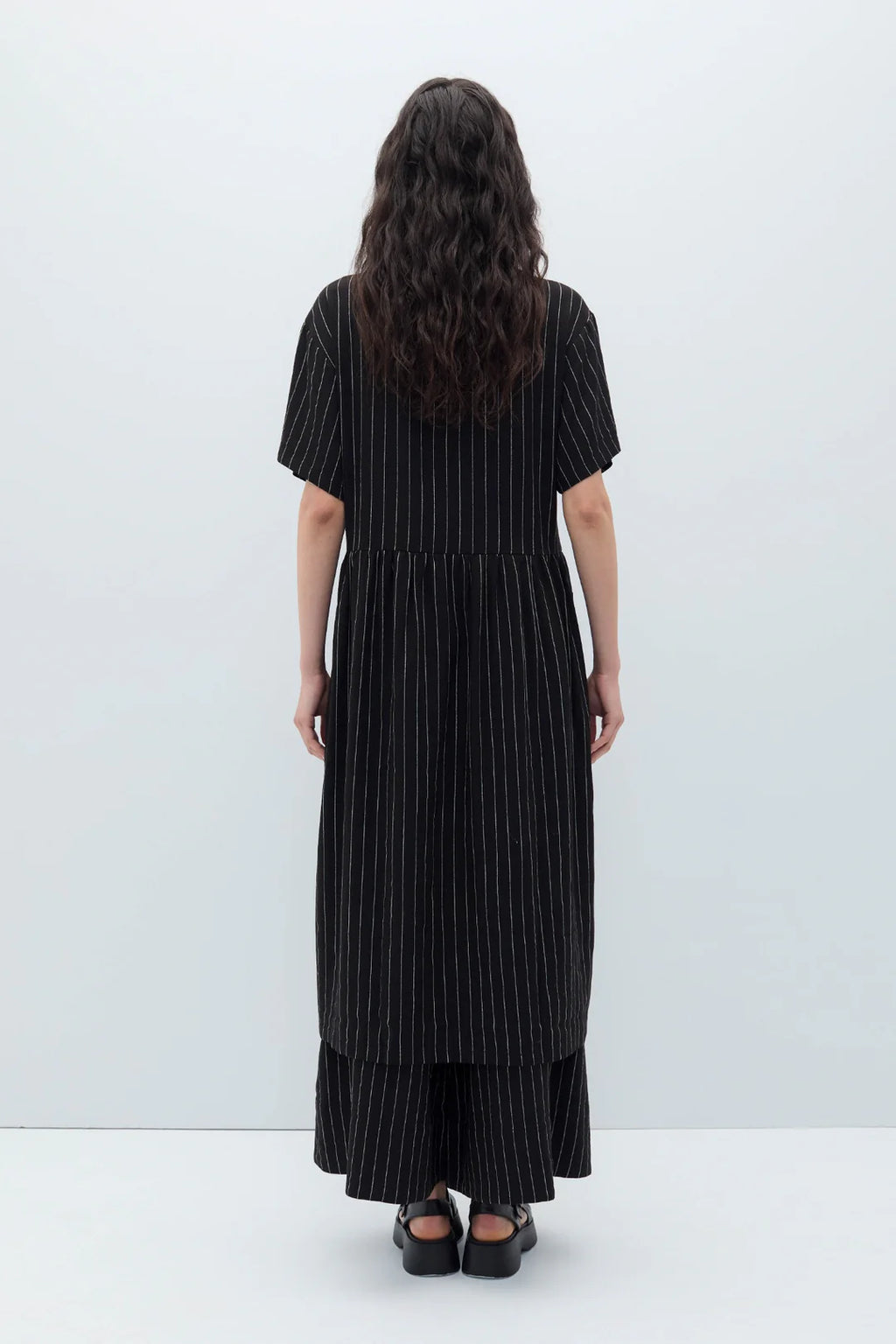 Woman wearing a black espelma pinstripe dress by Rita Row against a white background