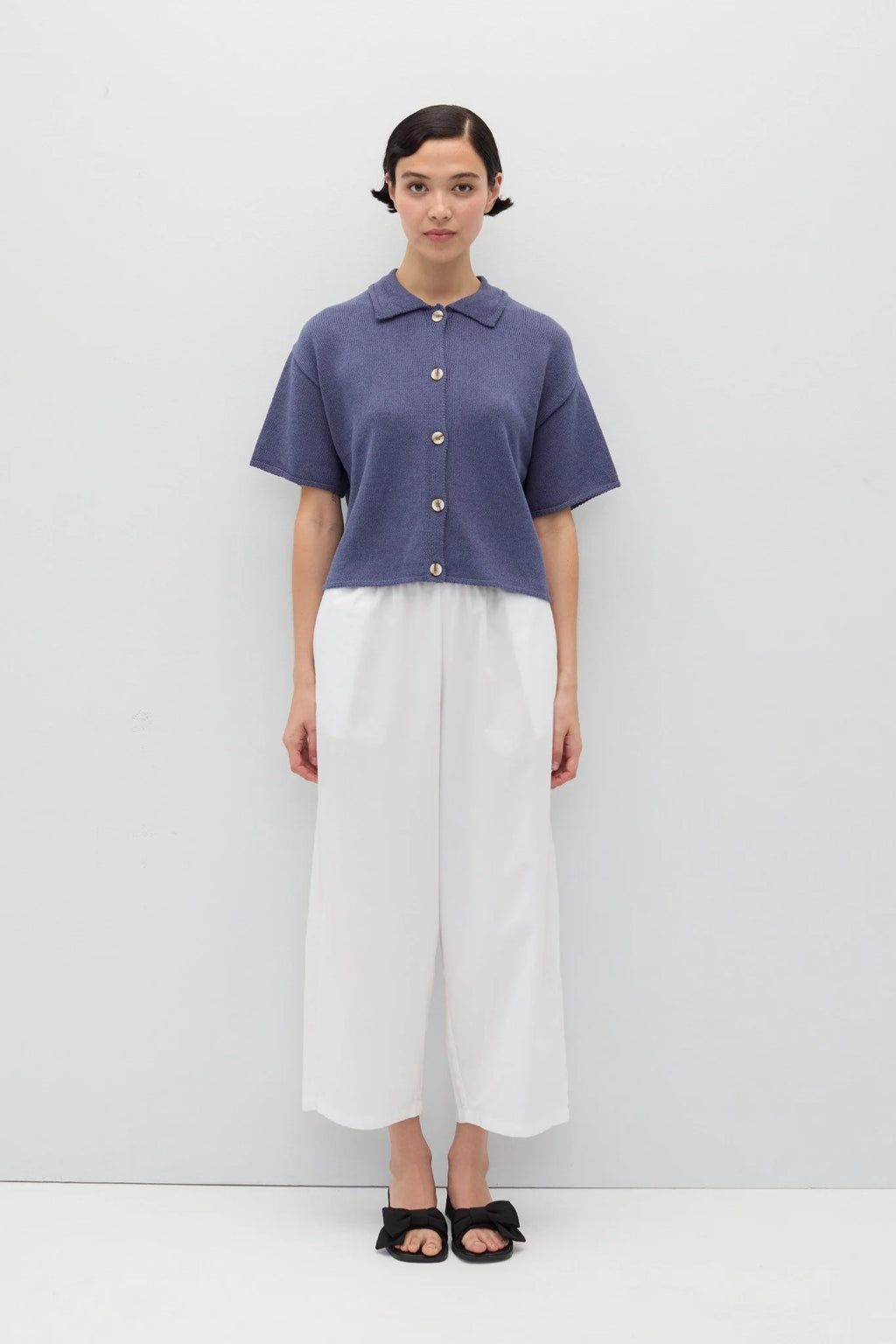 Person wearing a blue knit Eros button front shirt shirt by Rita Row on a light gray background