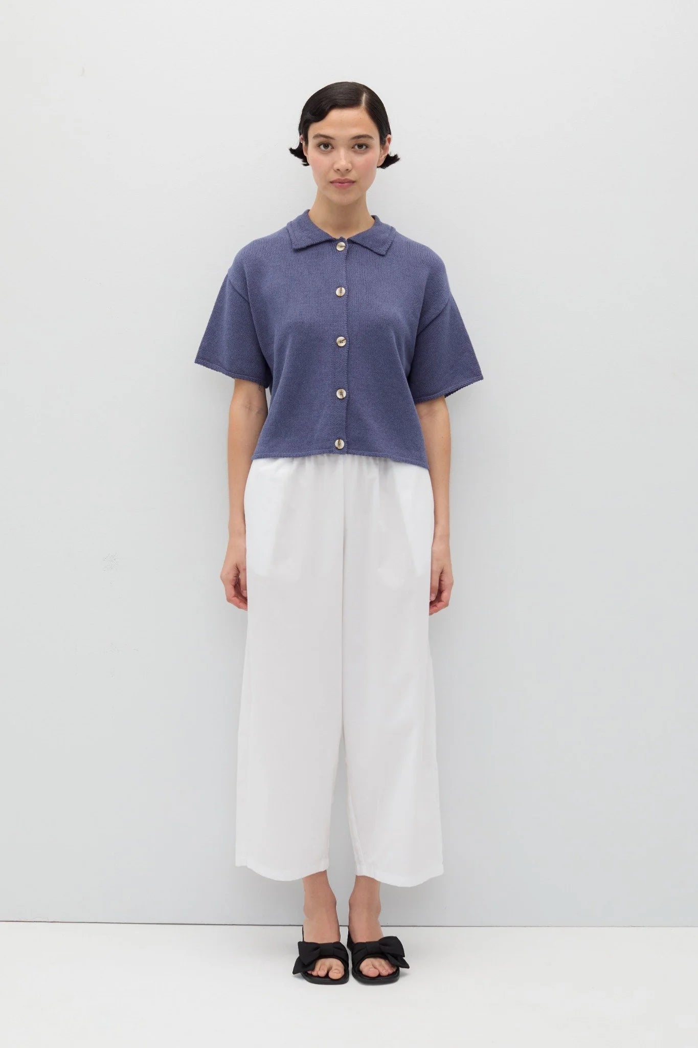 Person wearing a blue knit Eros button front shirt shirt by Rita Row on a light gray background