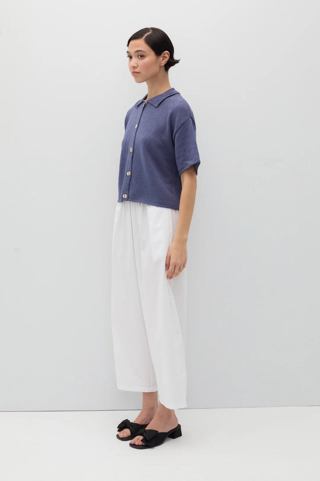 Person wearing a blue knit Eros button front shirt shirt by Rita Row on a light gray background
