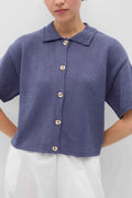 Person wearing a blue knit Eros button front shirt shirt by Rita Row on a light gray background