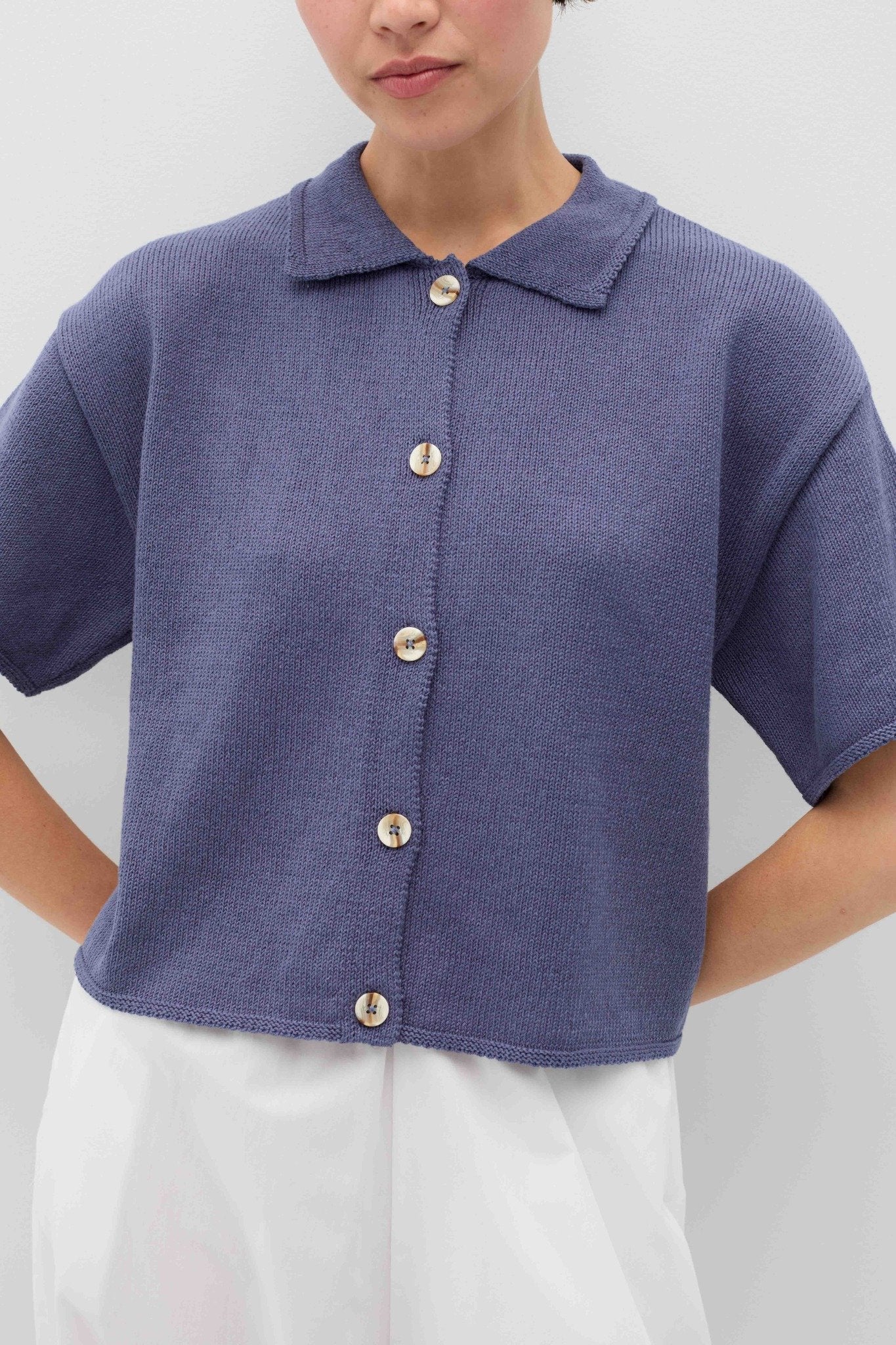 Person wearing a blue knit Eros button front shirt shirt by Rita Row on a light gray background