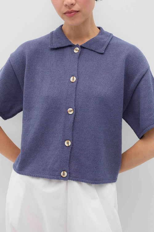Person wearing a blue knit Eros button front shirt shirt by Rita Row on a light gray background