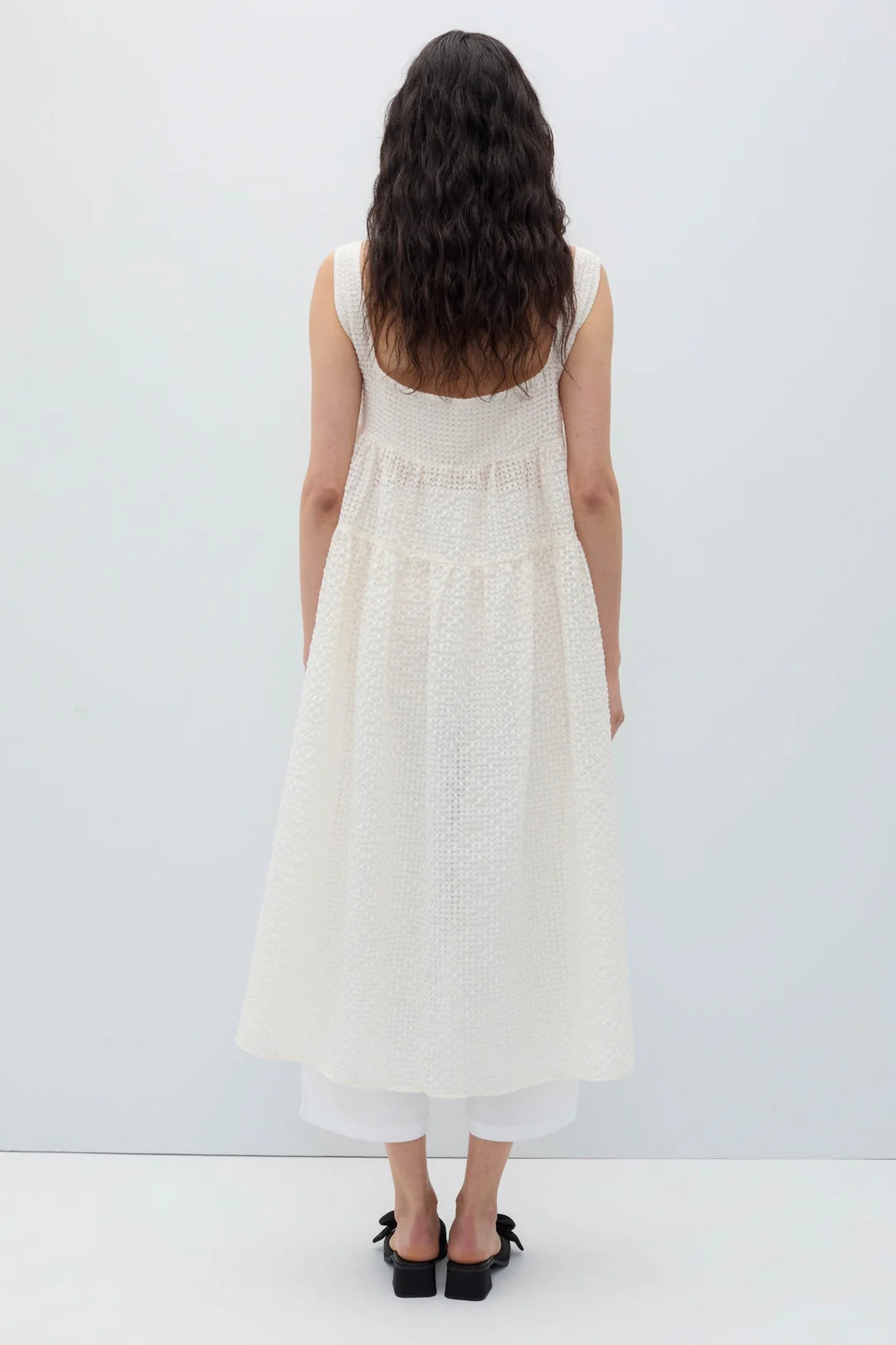Woman wearing a white sleeveless Saint dress by Rita Row on a plain background