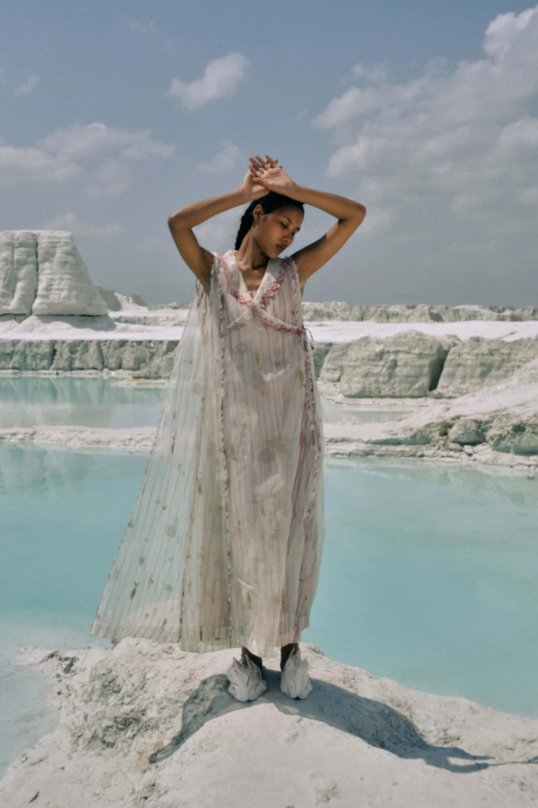 Woman in a flowing dress standing on a salt lake with salt formations in the background