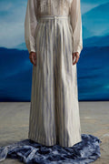Person wearing a long, light-colored dress with a blue background
