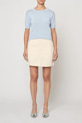 Woman wearing Pastel Blue Mari Top by Atelier Delphine and a cream skirt on a white background