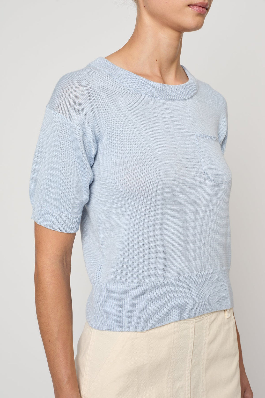 Woman wearing Pastel Blue Mari Top by Atelier Delphine and a cream skirt on a white background