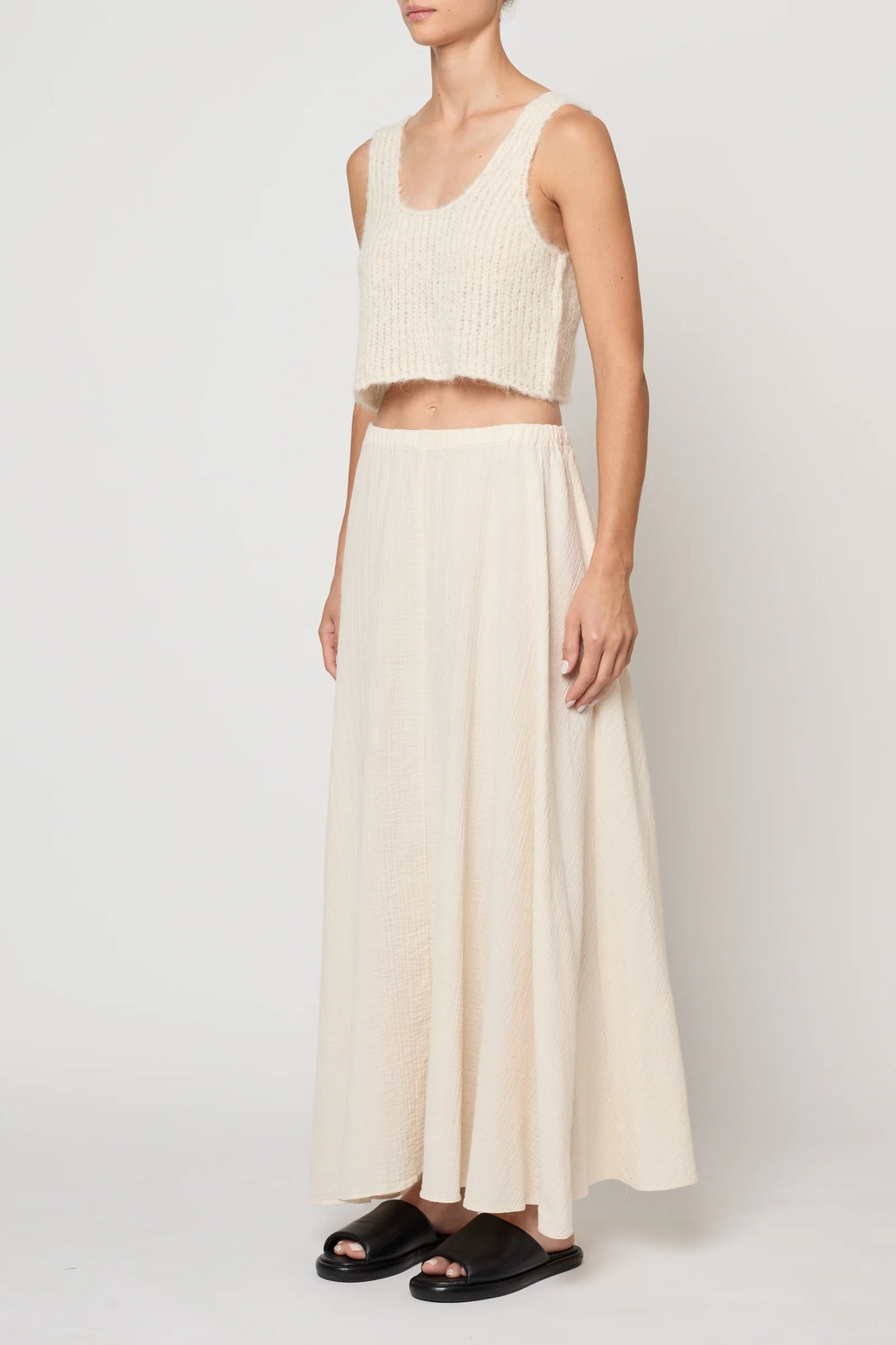 Woman wearing a cream knit tank by Atelier Delphine and a cream skirt