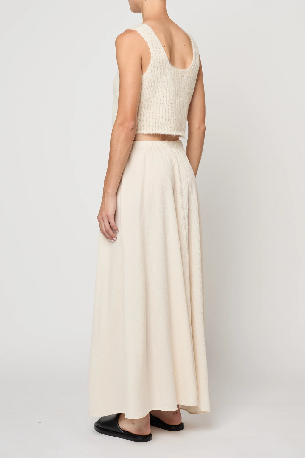 Woman wearing a cream knit tank by Atelier Delphine and a cream skirt