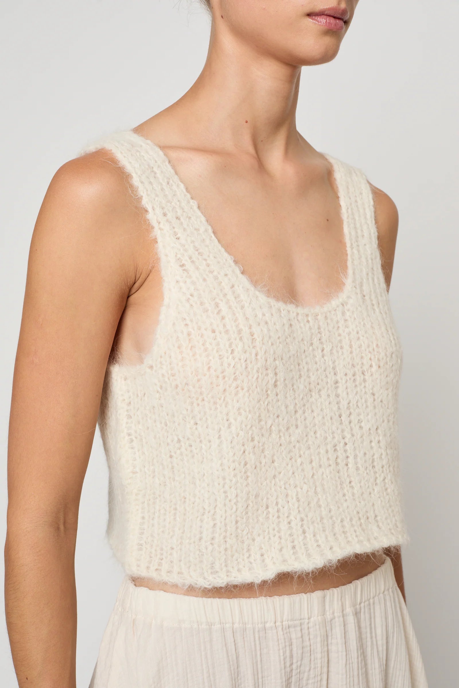 Woman wearing a cream knit tank by Atelier Delphine and a cream skirt