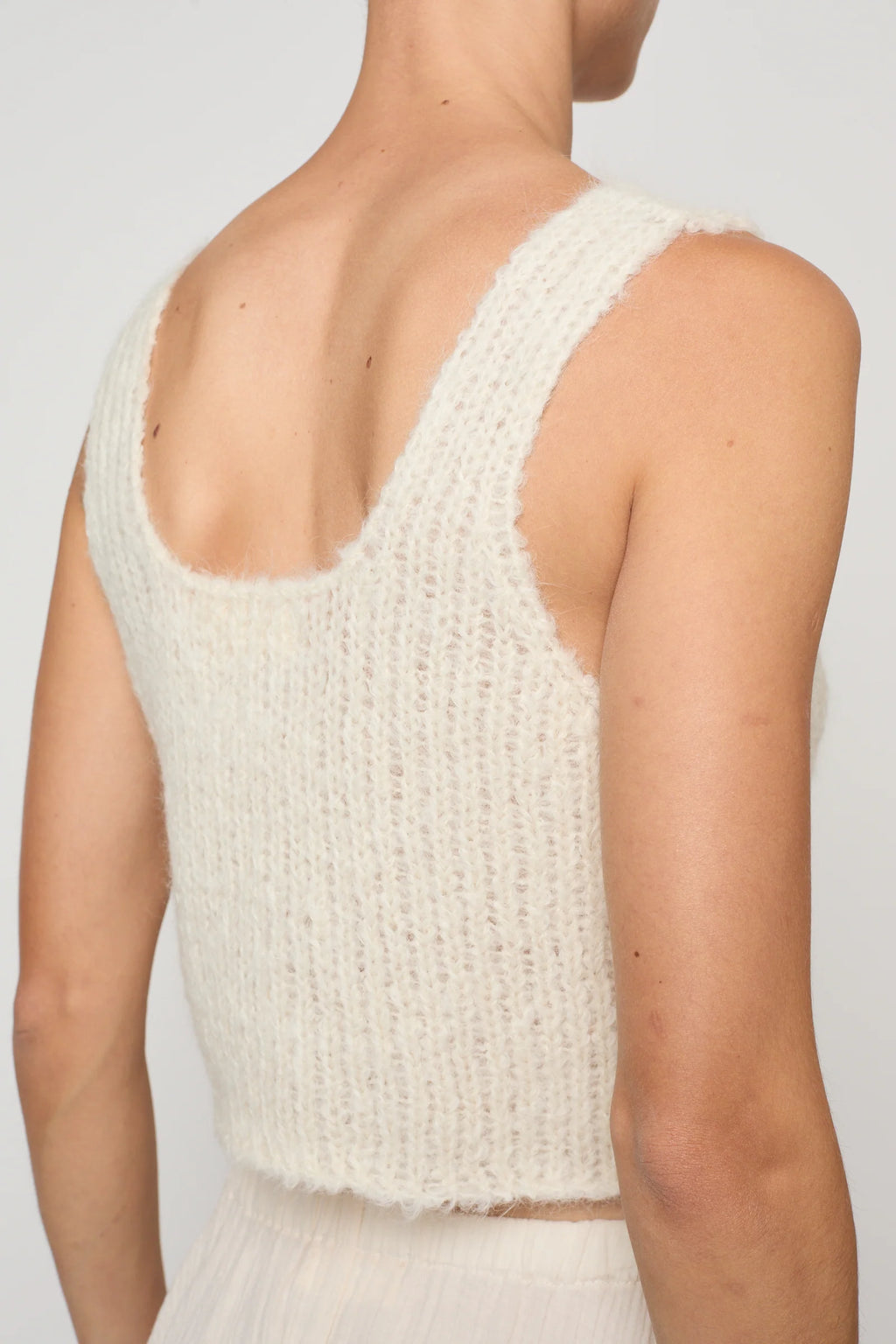 Woman wearing a cream knit tank by Atelier Delphine and a cream skirt