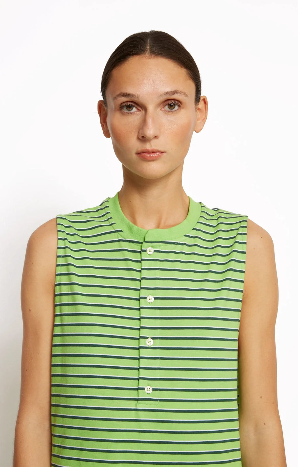 Woman wearing a green striped sleeveless dress by Roseanna against a white background