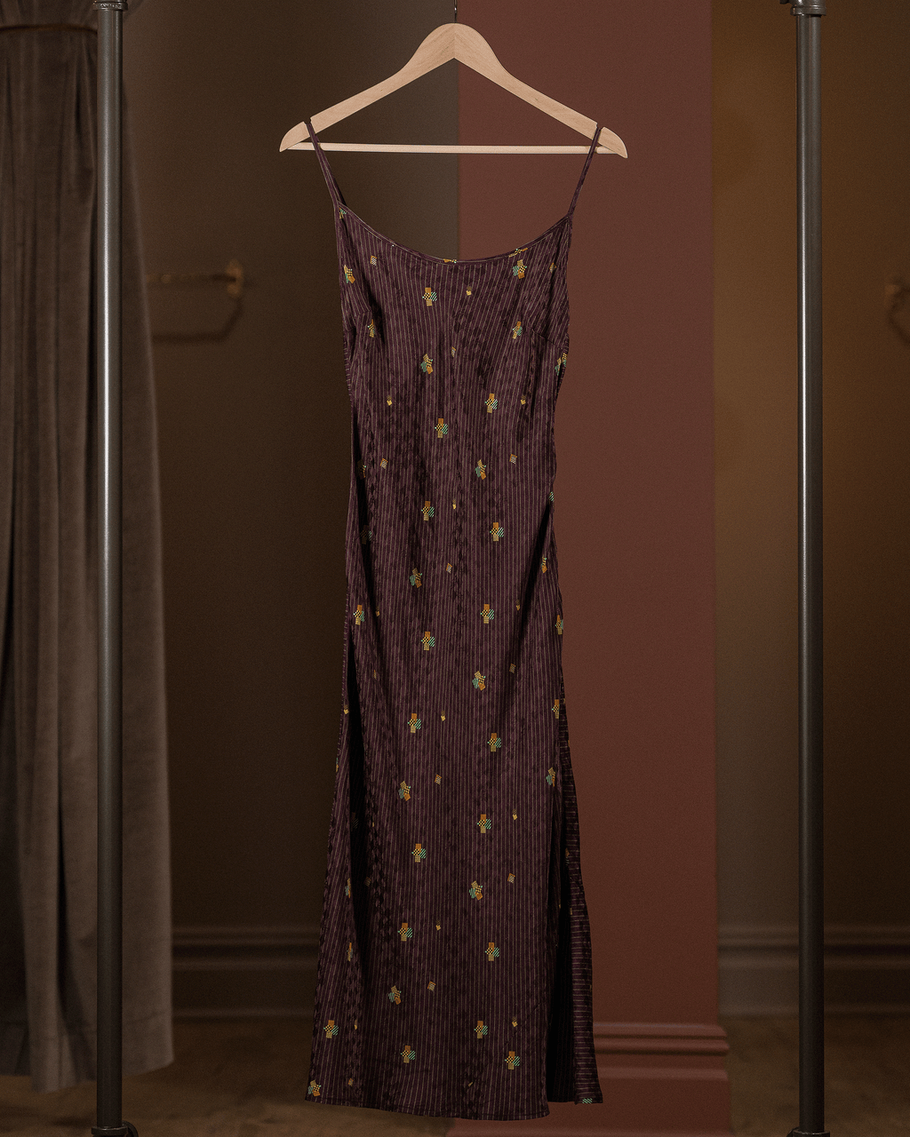 Purple dress with gold patterns on a hanger against a brown background