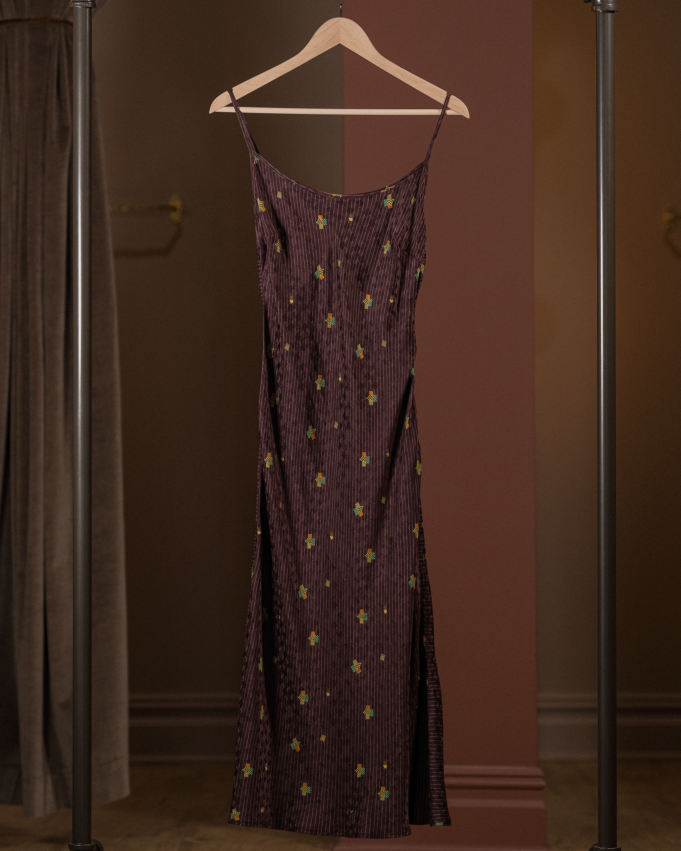 Purple dress with gold patterns on a hanger against a brown background