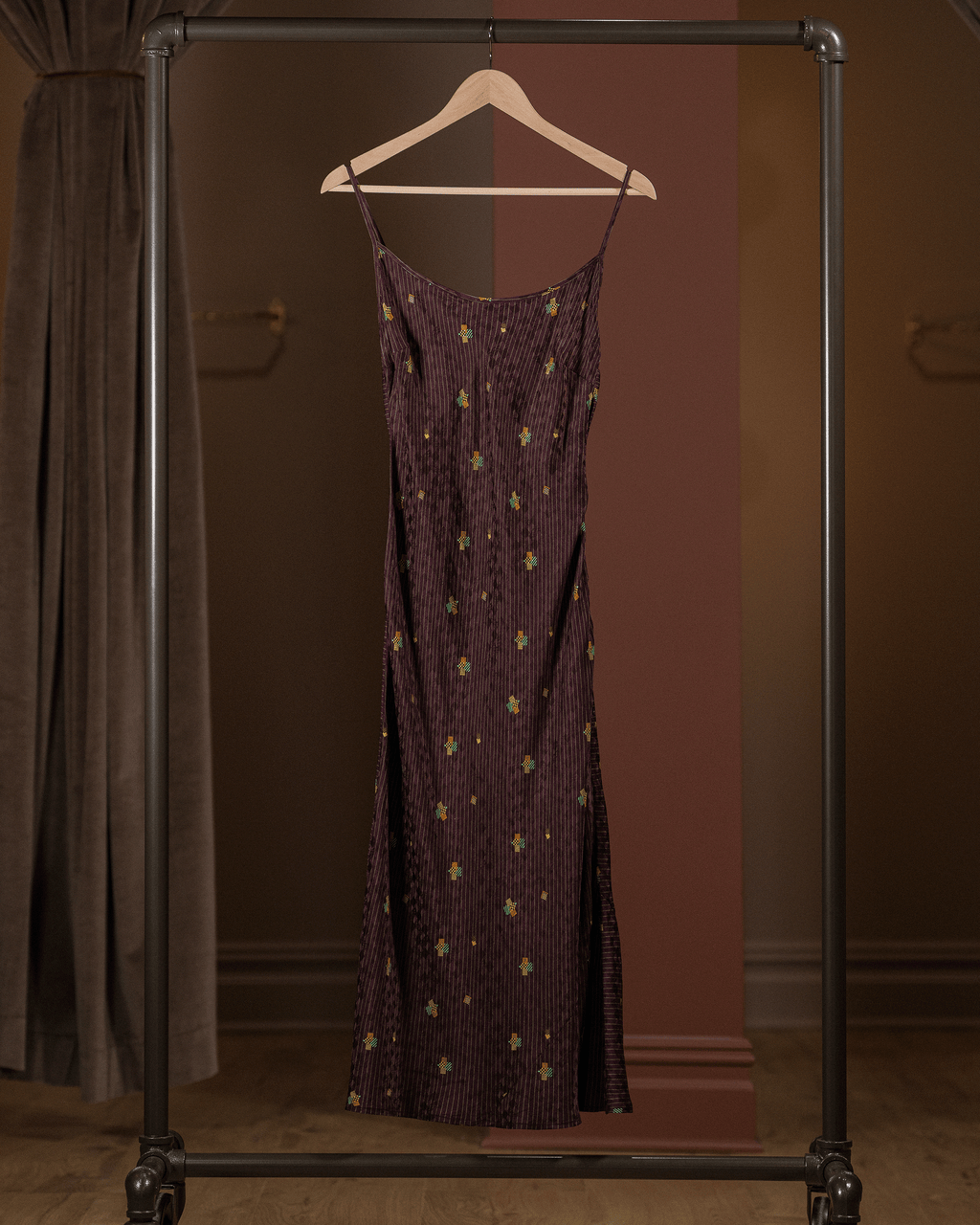 Purple dress with gold patterns on a hanger against a brown background