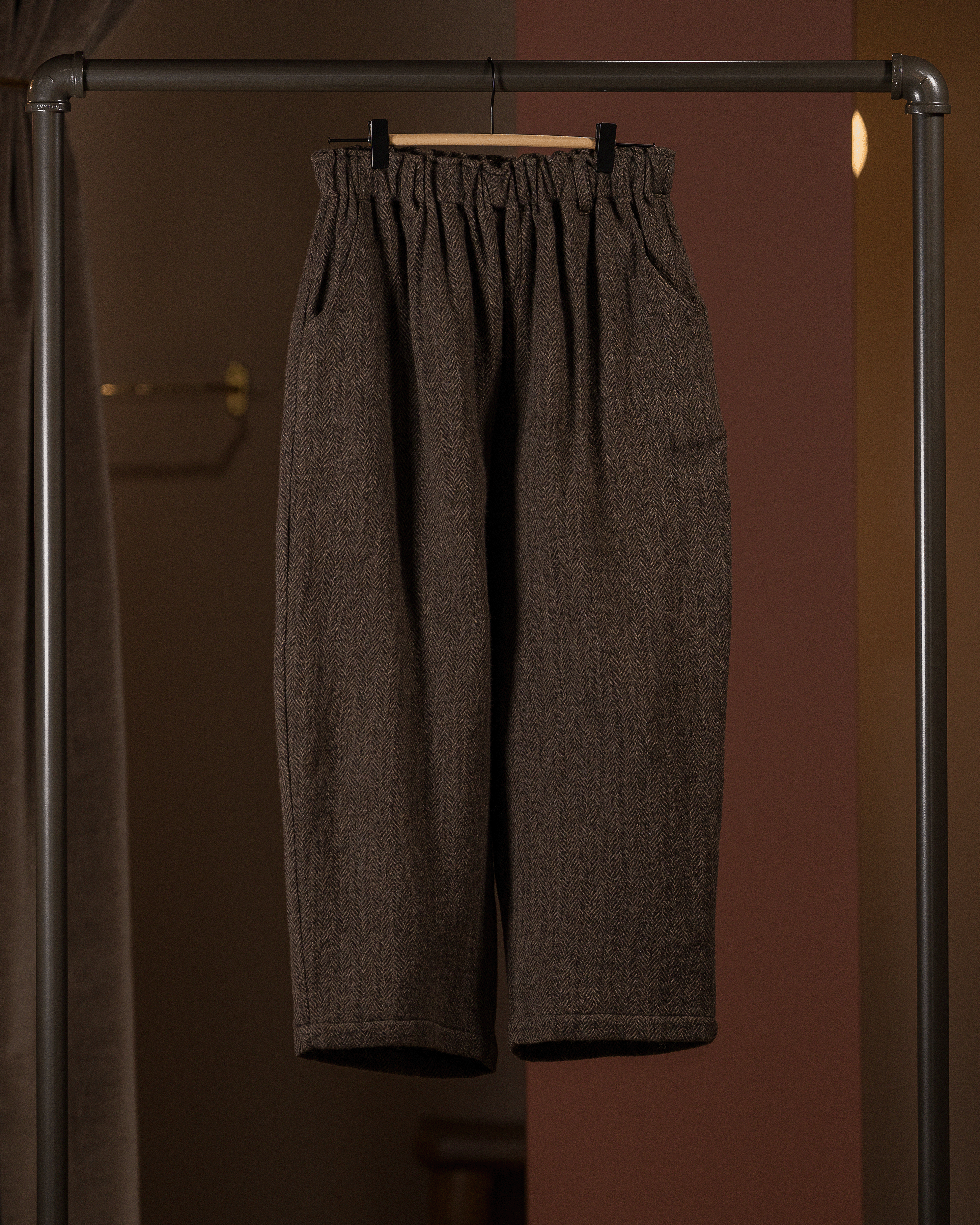 Brown pants hanging on a rack against a brown background