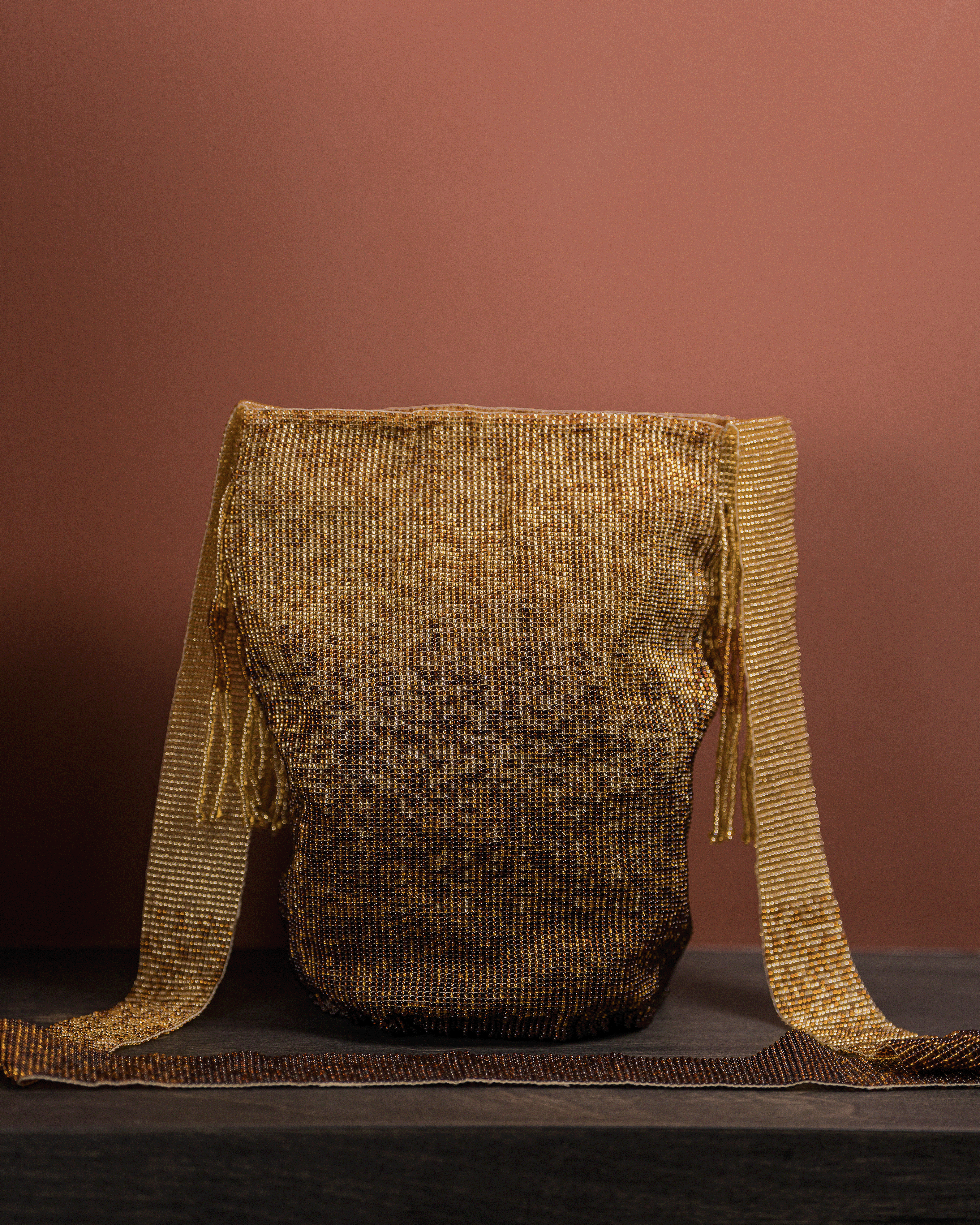 Gold textured bag with fringes on a brown background