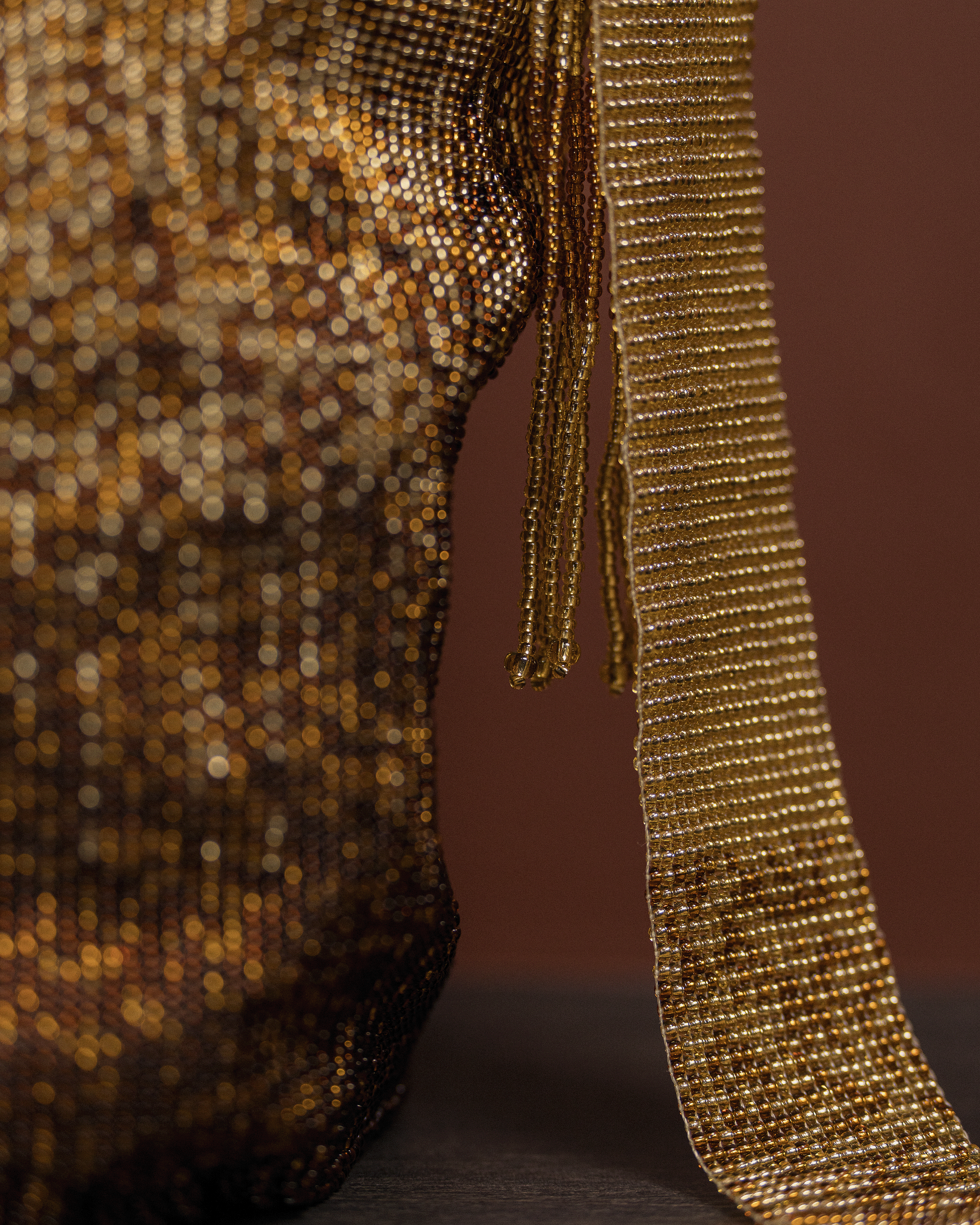Close-up of a gold sequin dress with a brown background