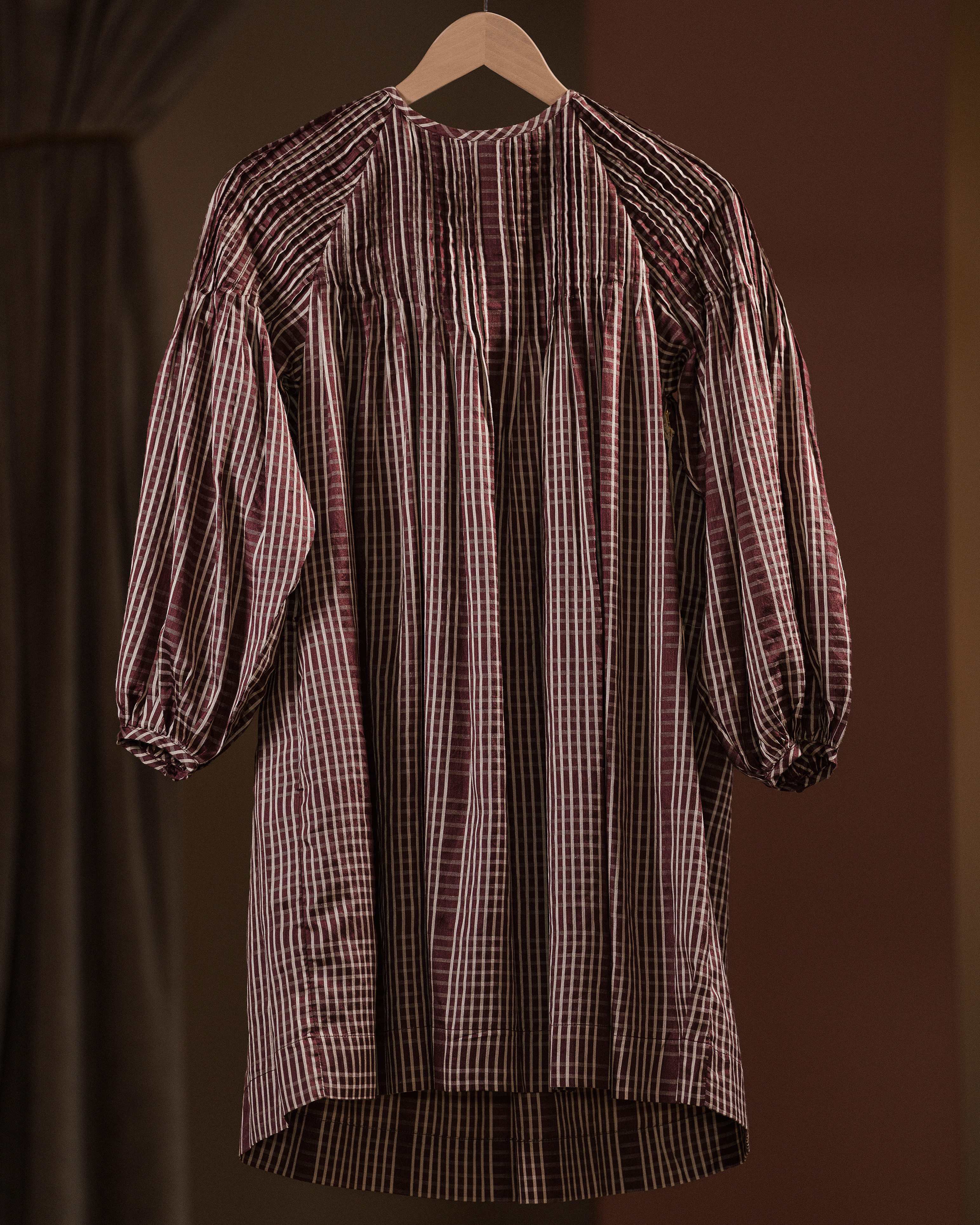 Plaid dress on a hanger against a brown background