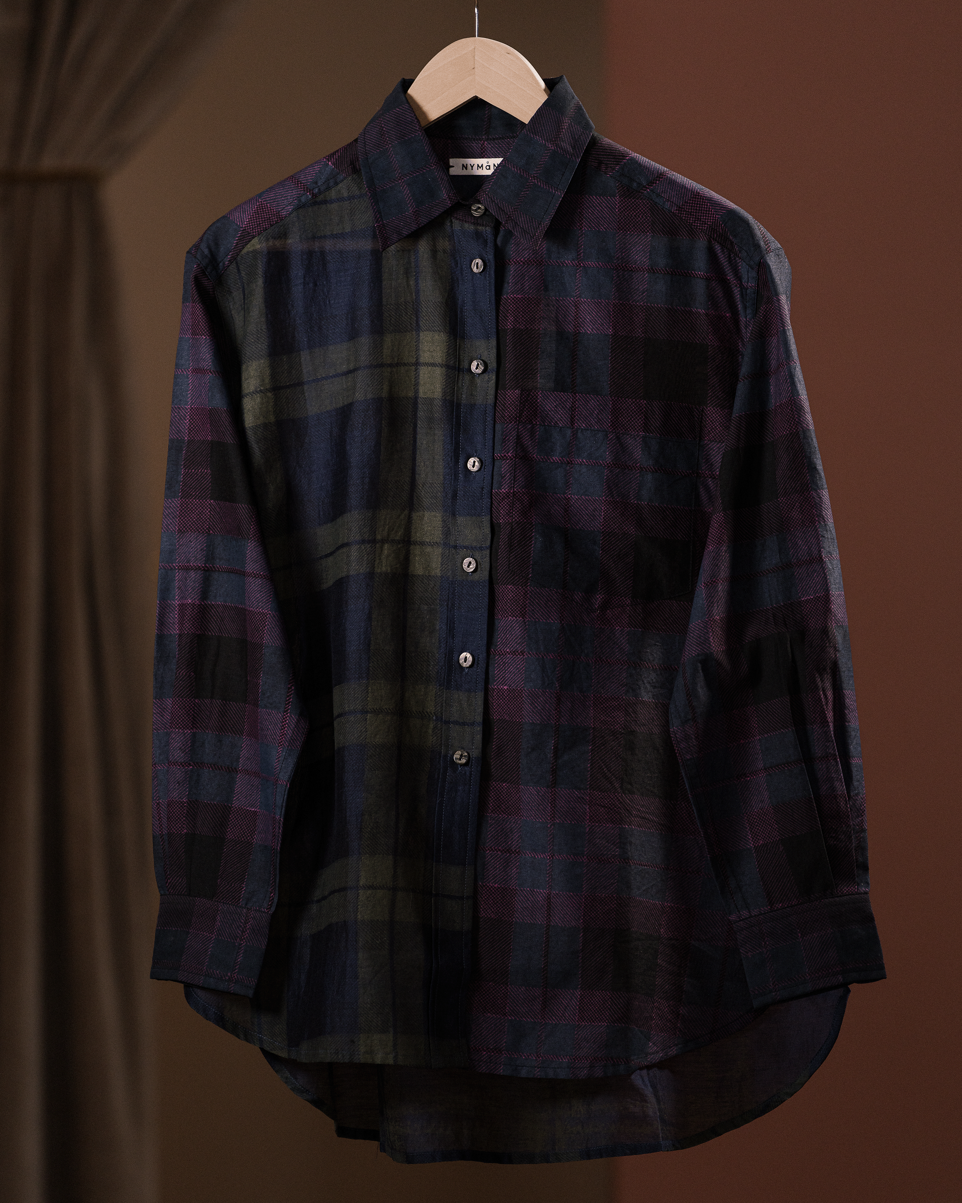 Plaid shirt on a hanger against a brown background