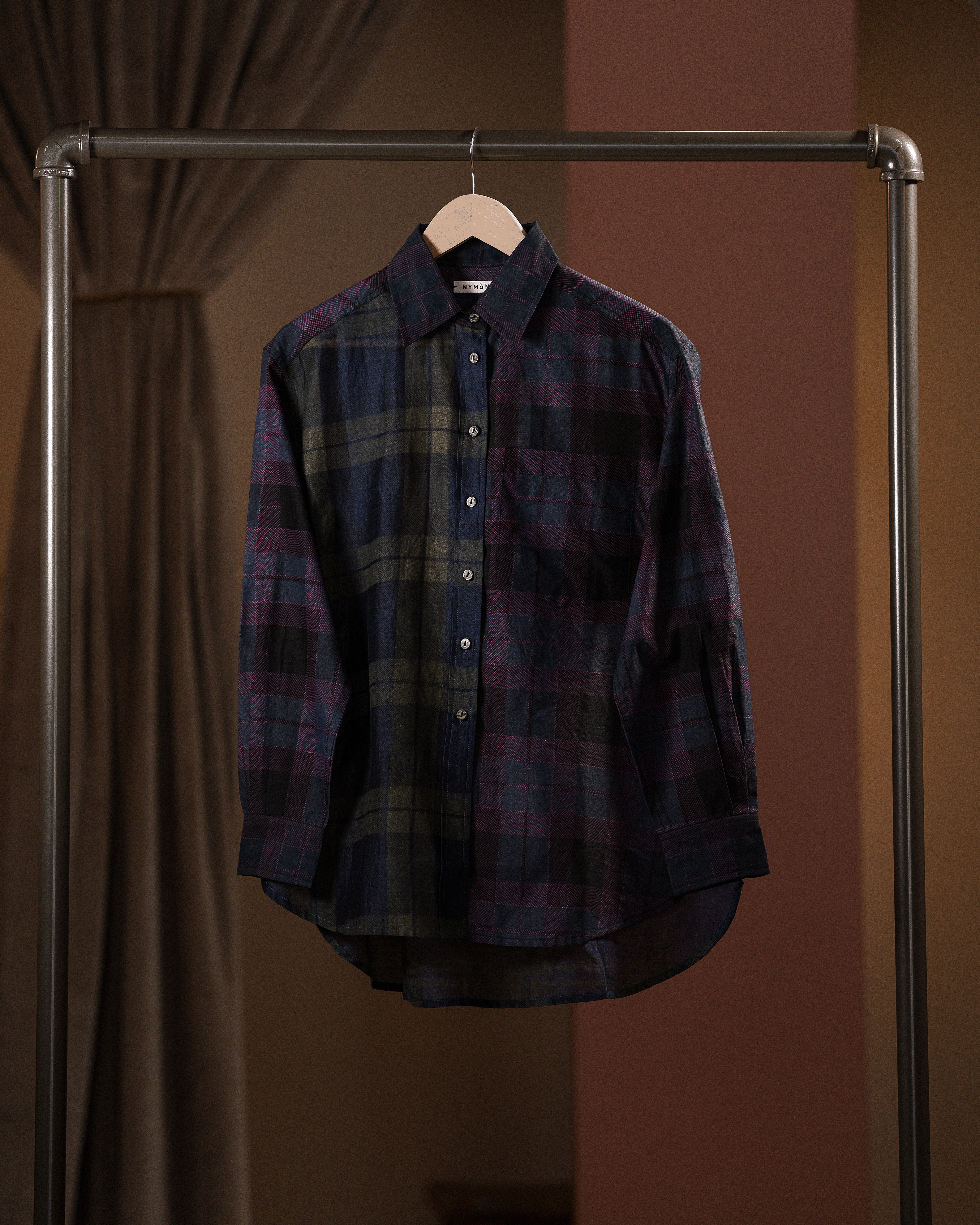 Plaid shirt hanging on a rack against a brown background