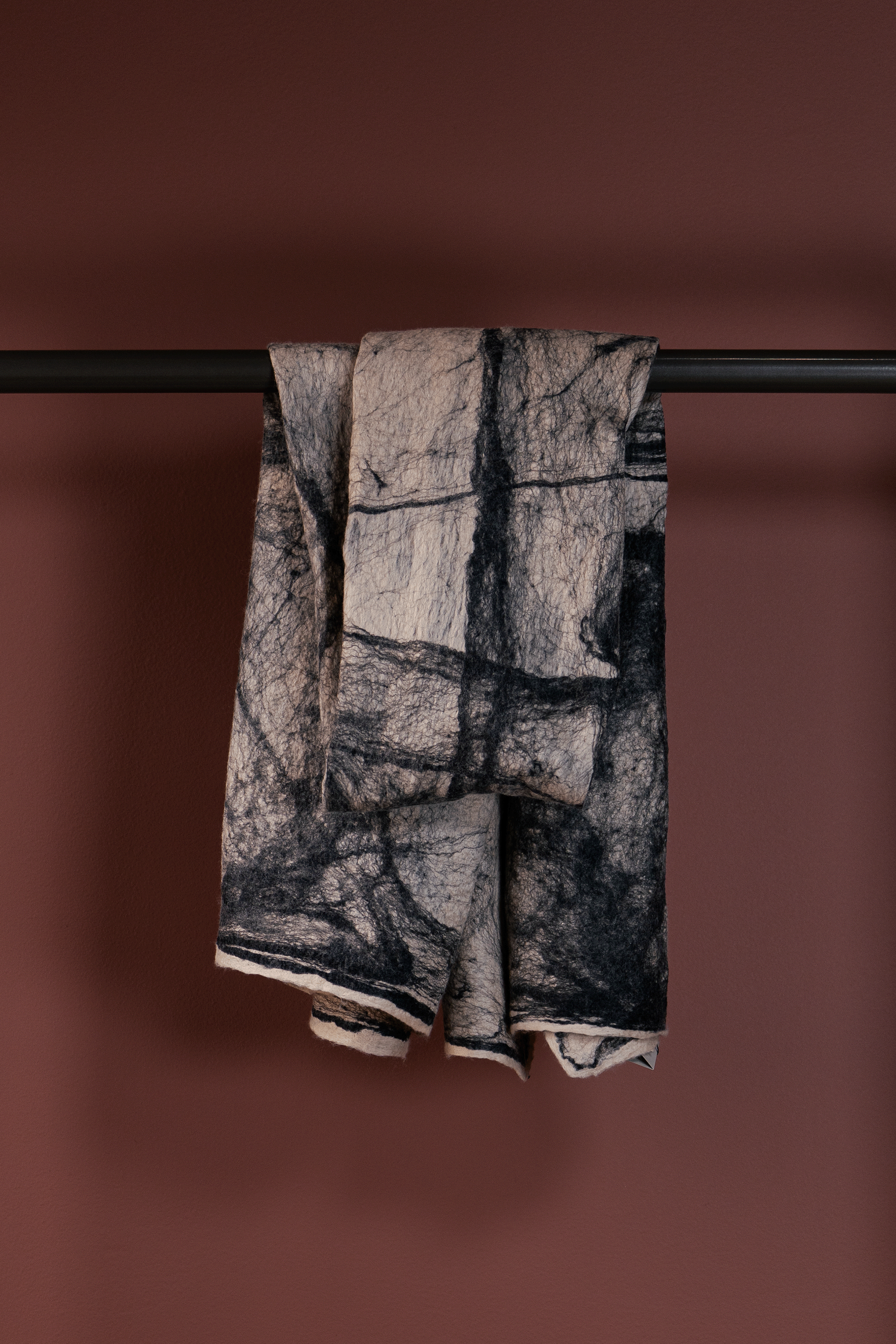 Textured towel hanging on a rod against a brown background