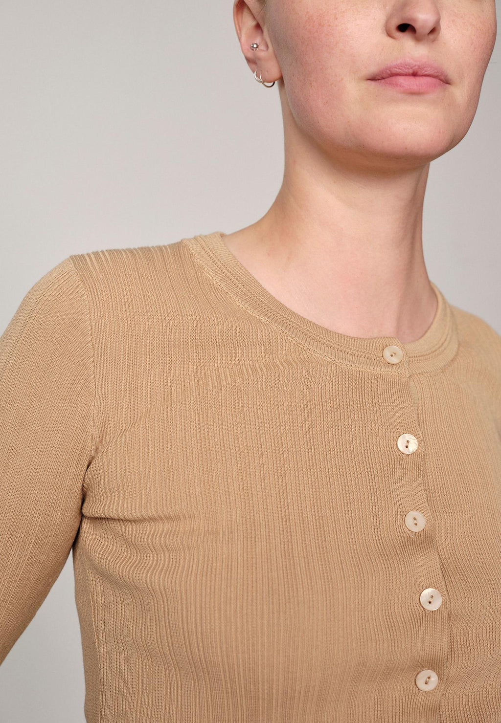 Woman wearing a sand ribbed Brooks sweater blouse by Herskind against a plain background