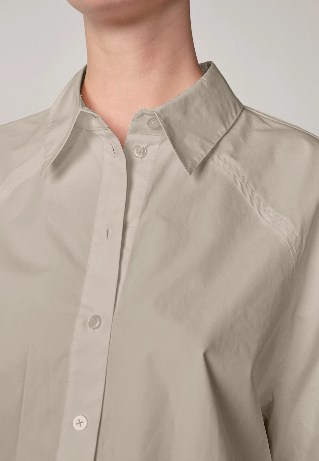 Woman wearing an oyster white Elsie shirt by Herskind and black skirt against a plain background