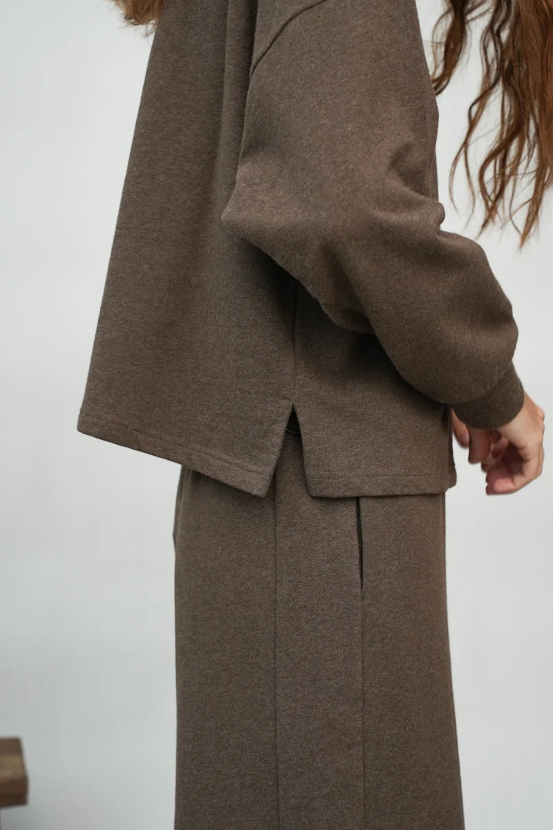 A woman wearing the Holly brown collared Sweatshirt by Beaumont Organic with matching pants.