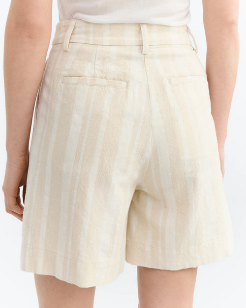 Raw Beige with white stripes shorts worn by a person on a white background.  Back pocket detail.