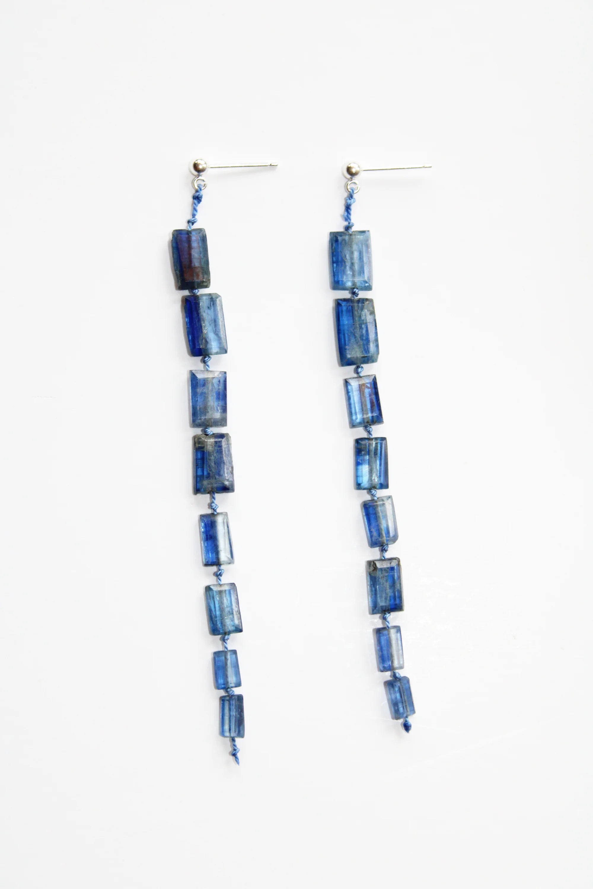 Blue drop midnight earrings against a plain background