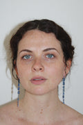 Woman with blue drop midnight earrings against a plain background