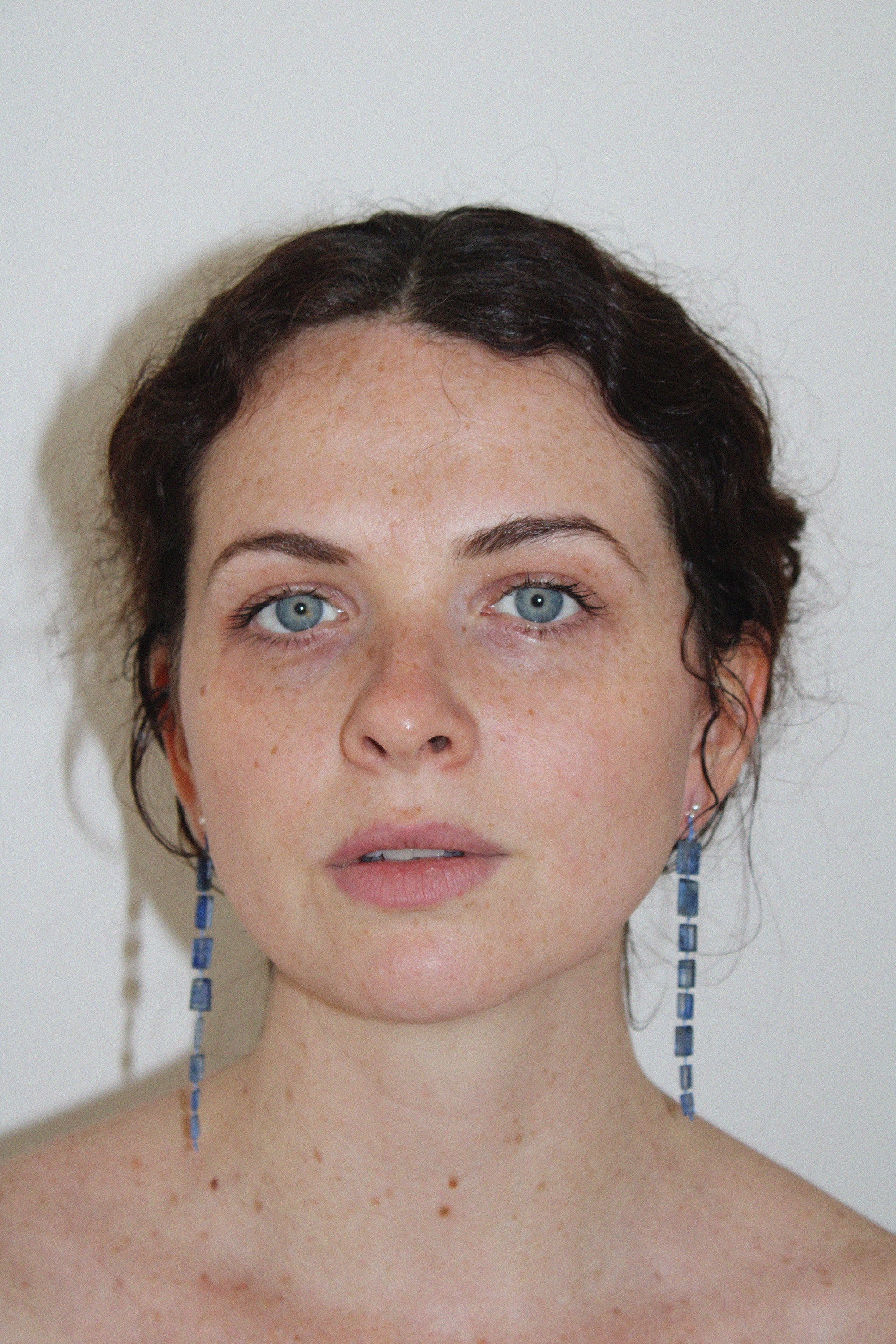 Woman with blue drop midnight earrings against a plain background
