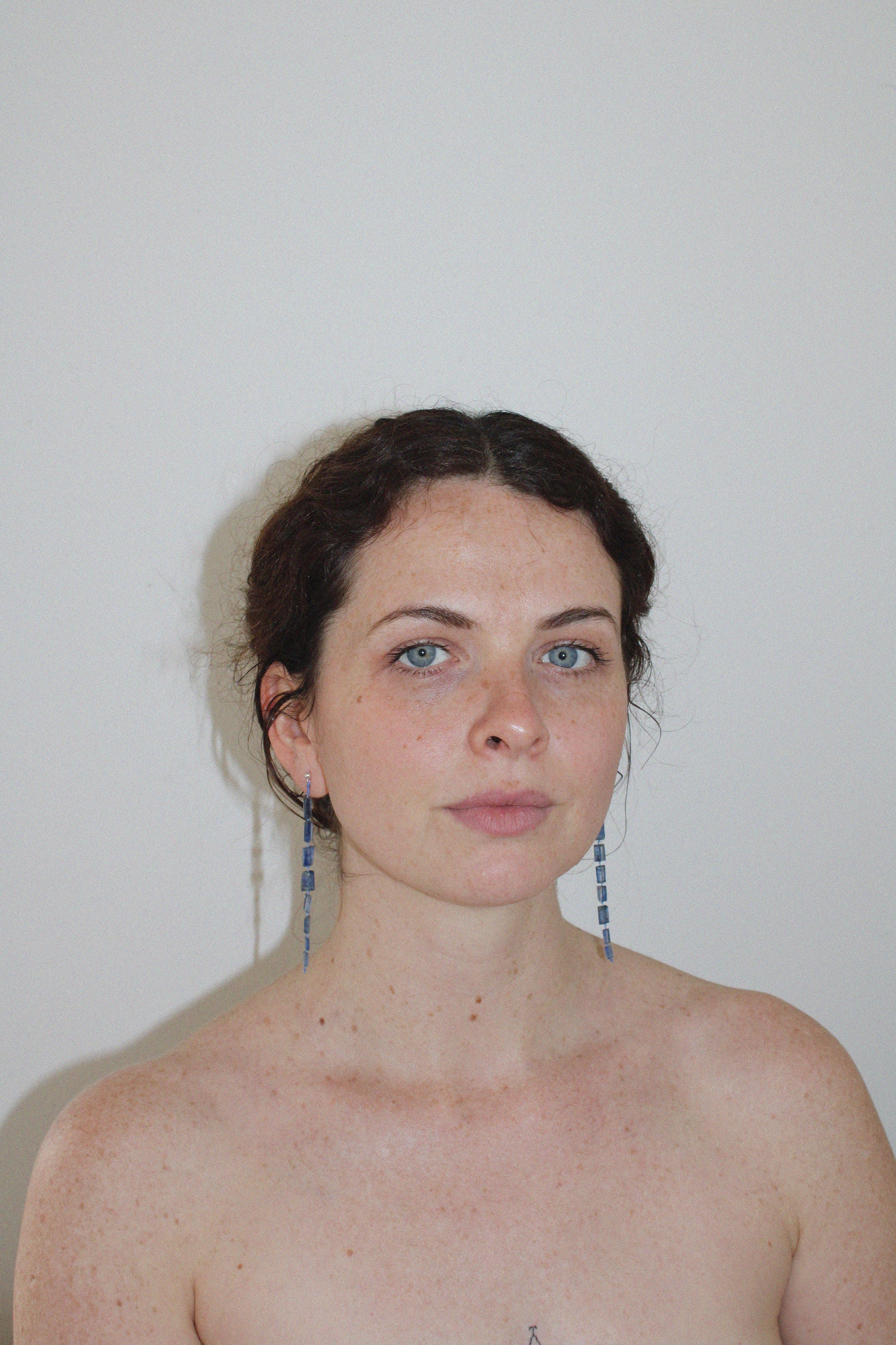 Woman with blue drop midnight earrings against a plain background