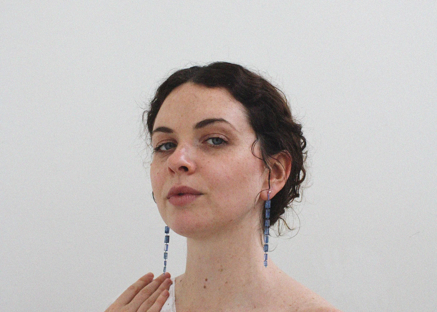 Woman with blue drop midnight earrings against a plain background