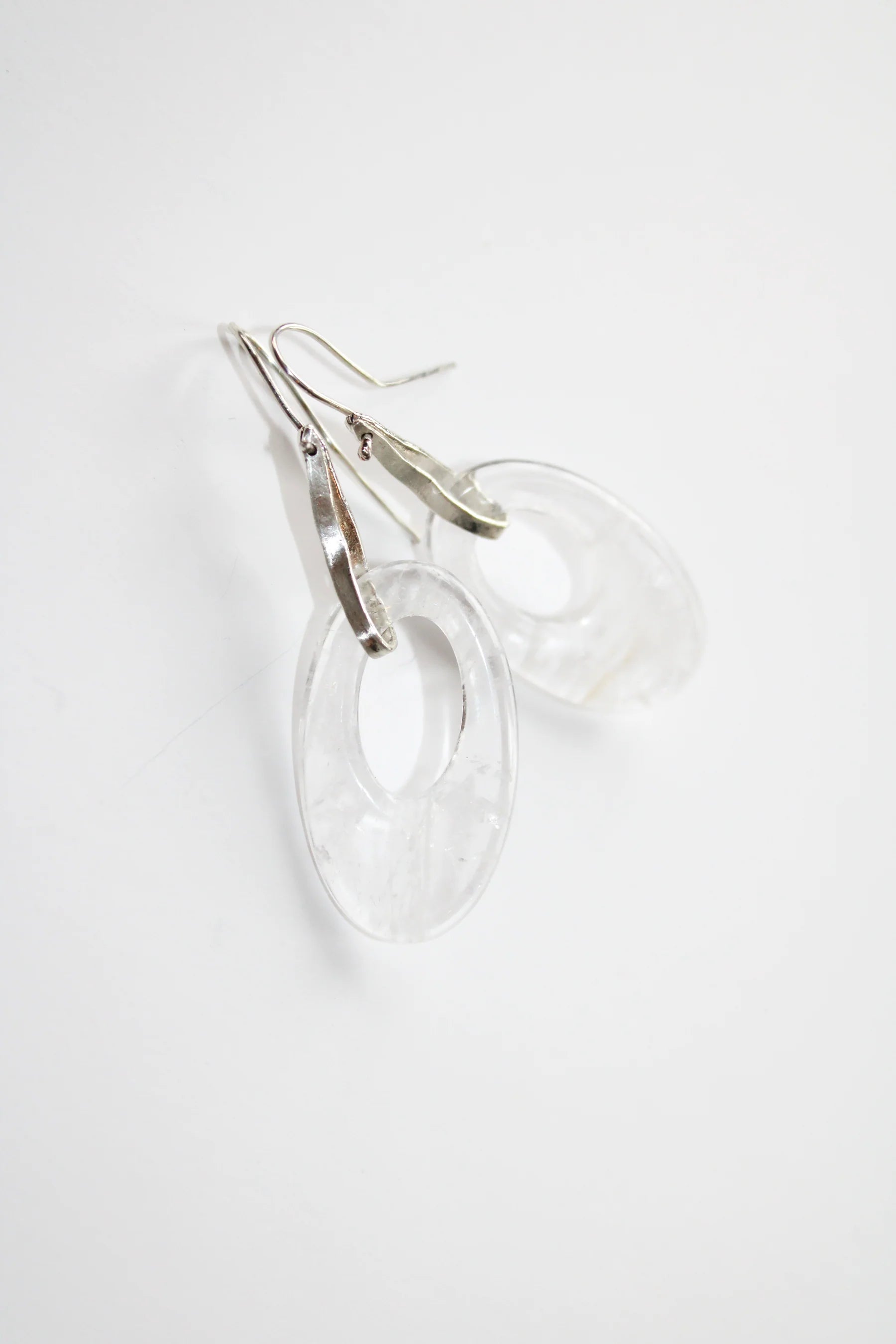A woman in profile wearing a clear, teardrop-shaped dangle moonlight earring by Takara, on a white background
