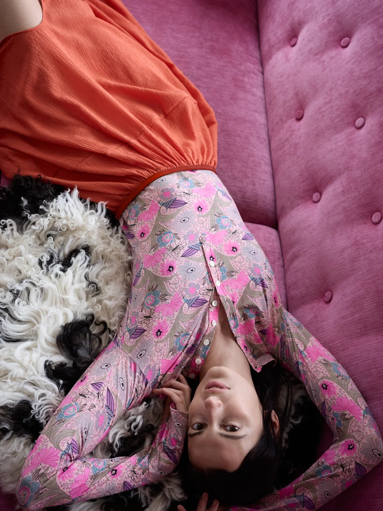 Person wearing pink pajama pants with a floral pattern on a pink couch.