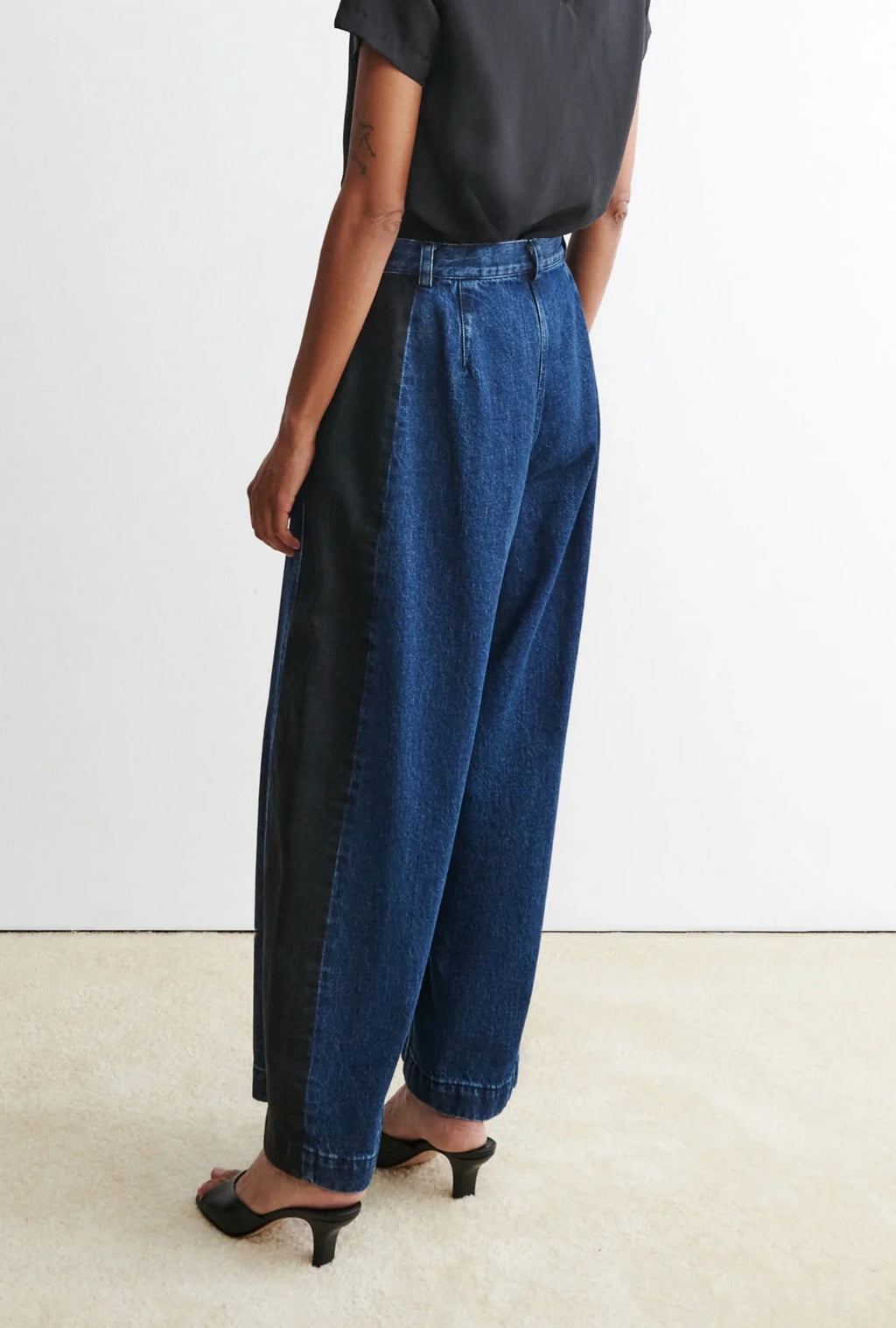 Person wearing a black t-shirt and blue garra jeans by Rachael Comey against a white background