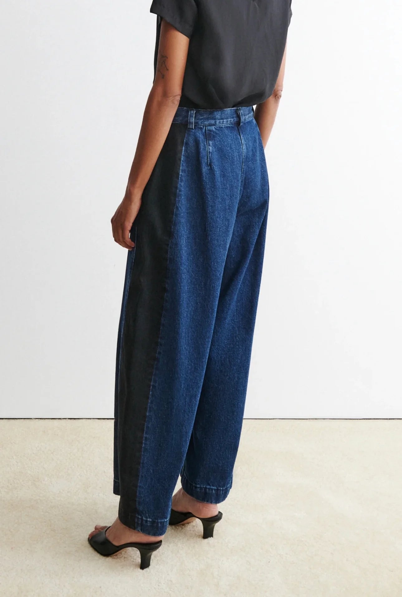 Person wearing a black t-shirt and blue garra jeans by Rachael Comey against a white background