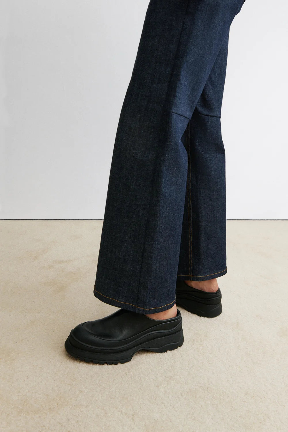 A model with jeans and Black leather Slip in Barla Mule by Rachel Comey.