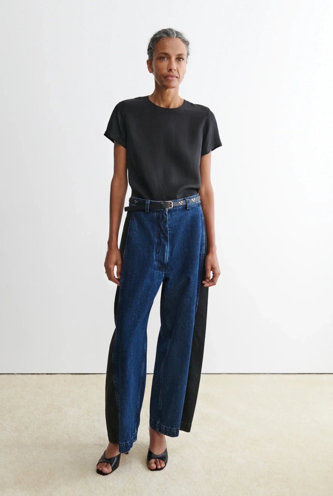 Person wearing a black t-shirt and blue garra jeans by Rachael Comey against a white background