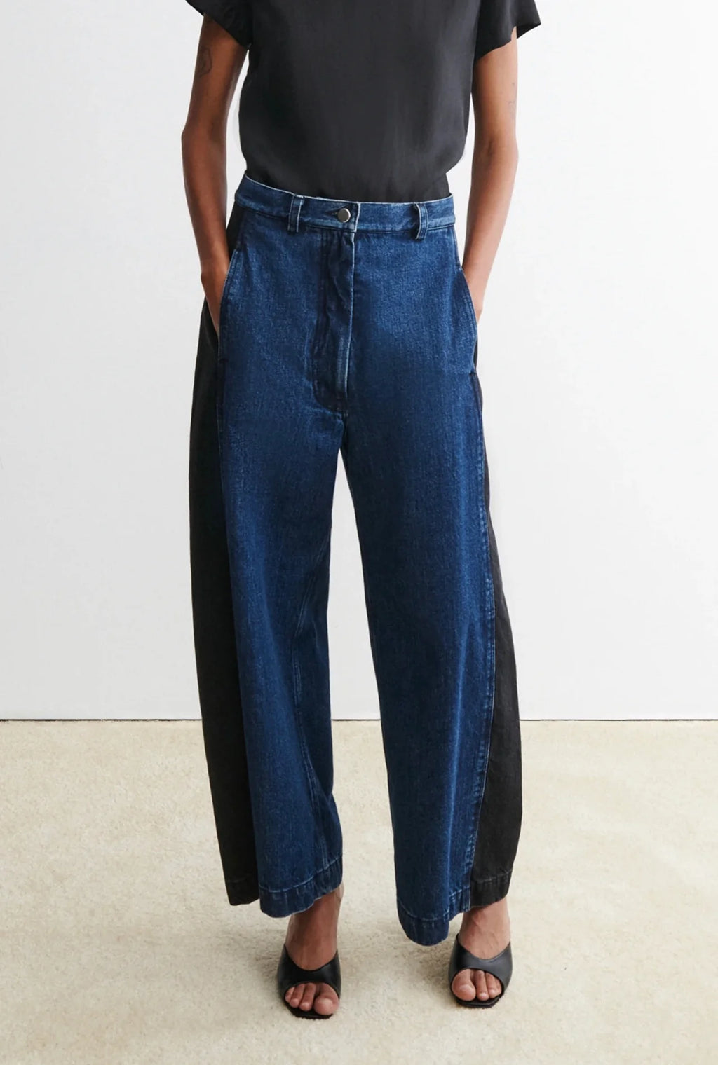 Person wearing a black t-shirt and blue garra jeans by Rachael Comey against a white background