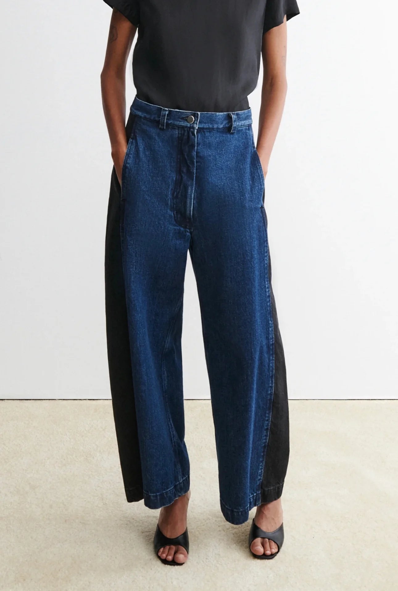 Person wearing a black t-shirt and blue garra jeans by Rachael Comey against a white background