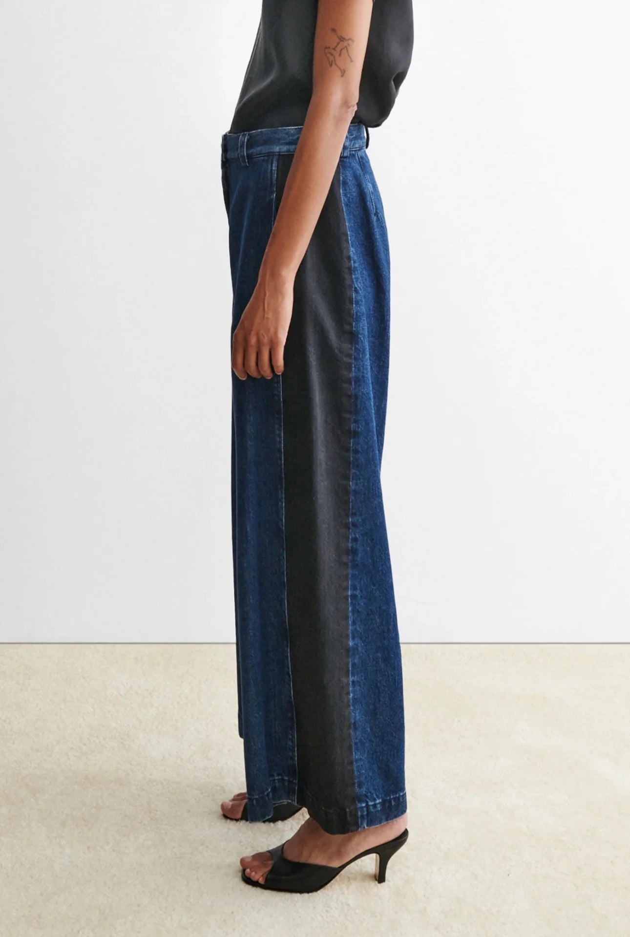 Person wearing a black t-shirt and blue garra jeans by Rachael Comey against a white background