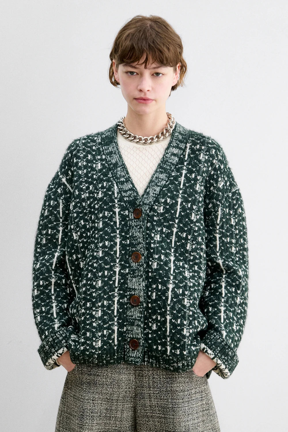 A Model wearing a forest fair isle knit Hedda Cardigan by Rachel Comey with grey shorts.