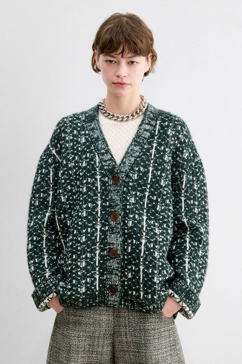 A Model wearing a forest fair isle knit Hedda Cardigan by Rachel Comey with grey shorts.