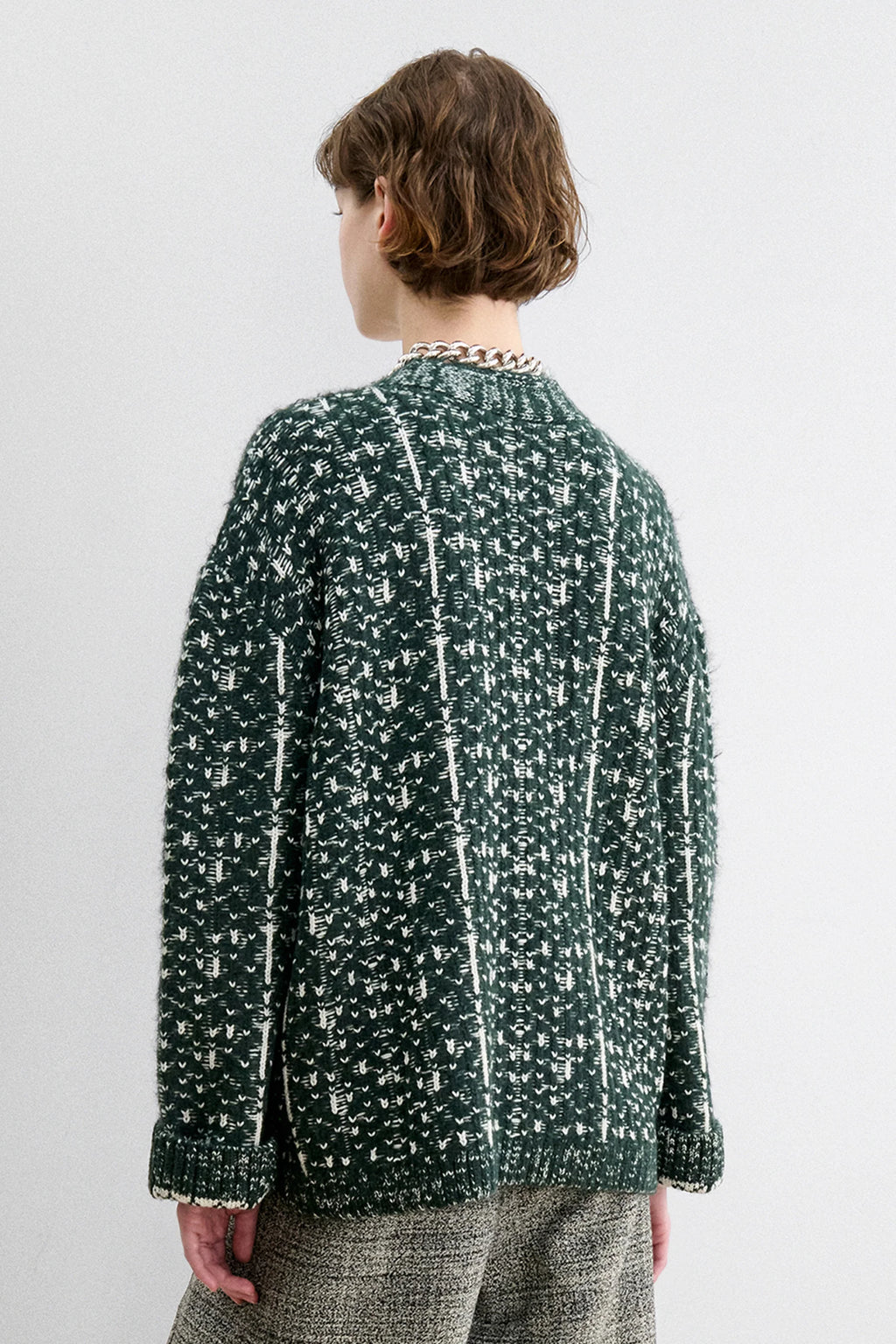 A Model wearing a forest fair isle knit Hedda Cardigan by Rachel Comey with grey shorts.