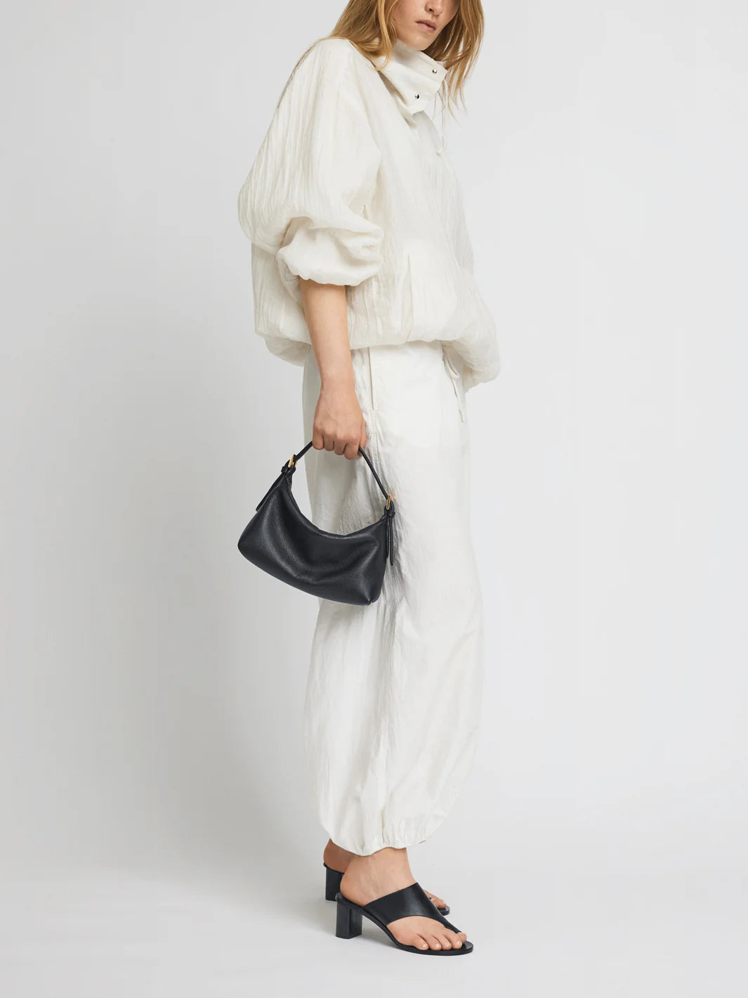 Person wearing lack cutout Rosate sandal by ATP Atelier with a high heel with a white outfit on a white background